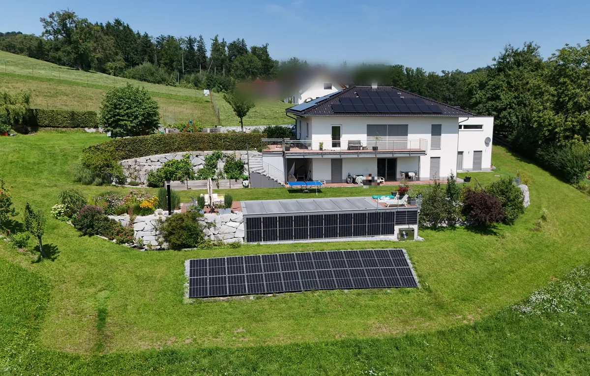 Einfamilienhaus mit Dachanlage, Freiflächen-PV und Pool aus der Luft